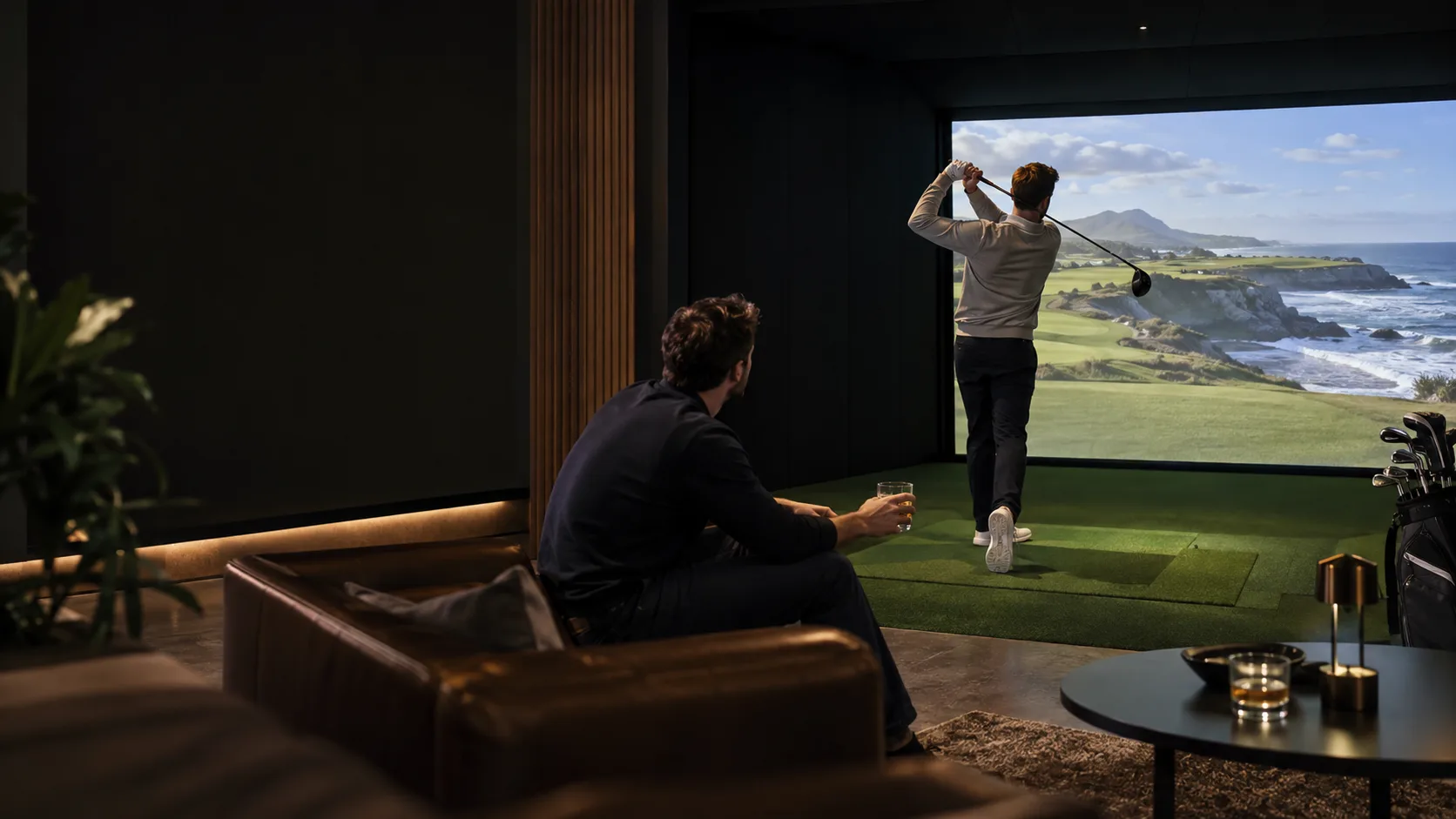 Friends playing in an indoor golf simulator bay
